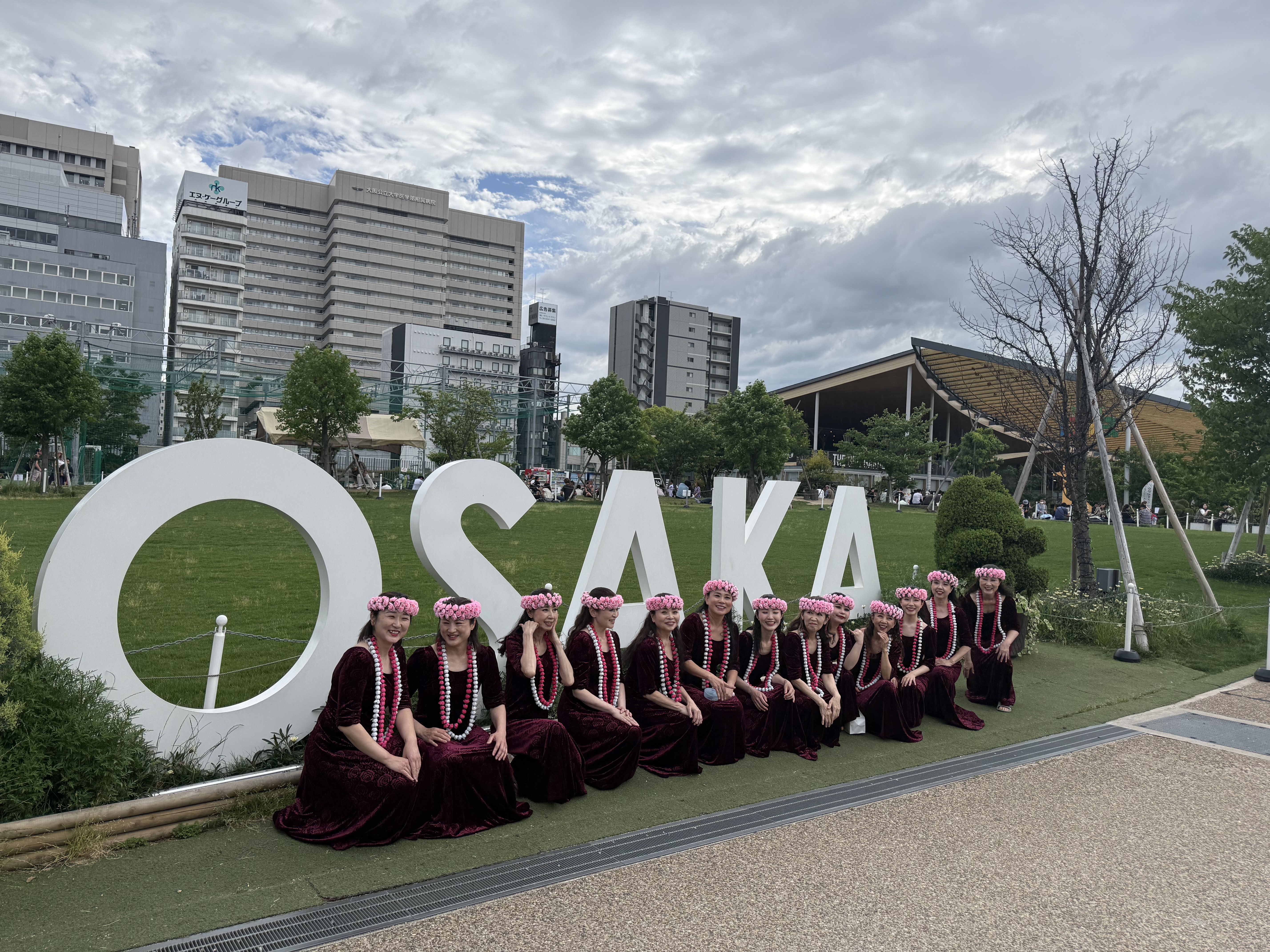 大阪のイベント会場でOSAKAサインの前に並ぶMohala He Liʻaのメンバー